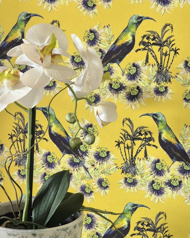 Floral and bird Kirimiri wallpaper in Golden Glow (yellow) with a potted orchid plant in the foreground