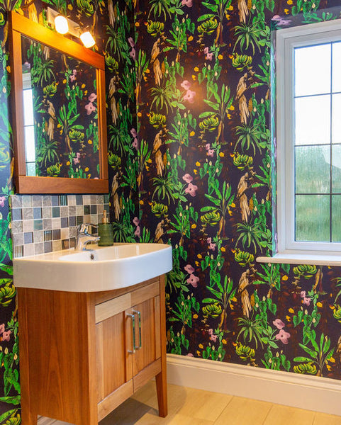Bathroom with colorful floral Kitito wallpaper, wooden vanity, and window.